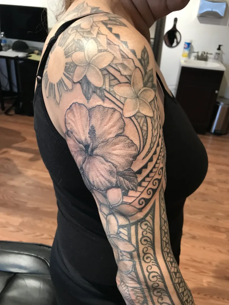 Hibiscus and plumeria shaded in grey, wrapped in Polynesian bands down the arm